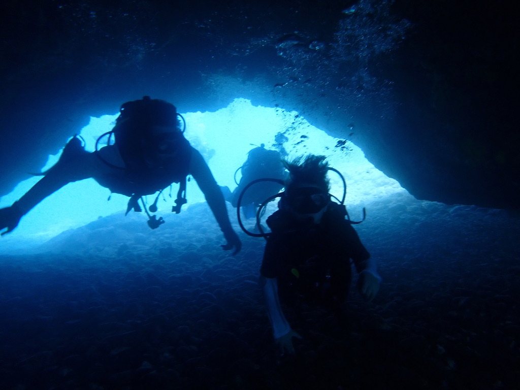 Divers silhouetted in the cavern entrance at Five Caves, Mākena, Maui