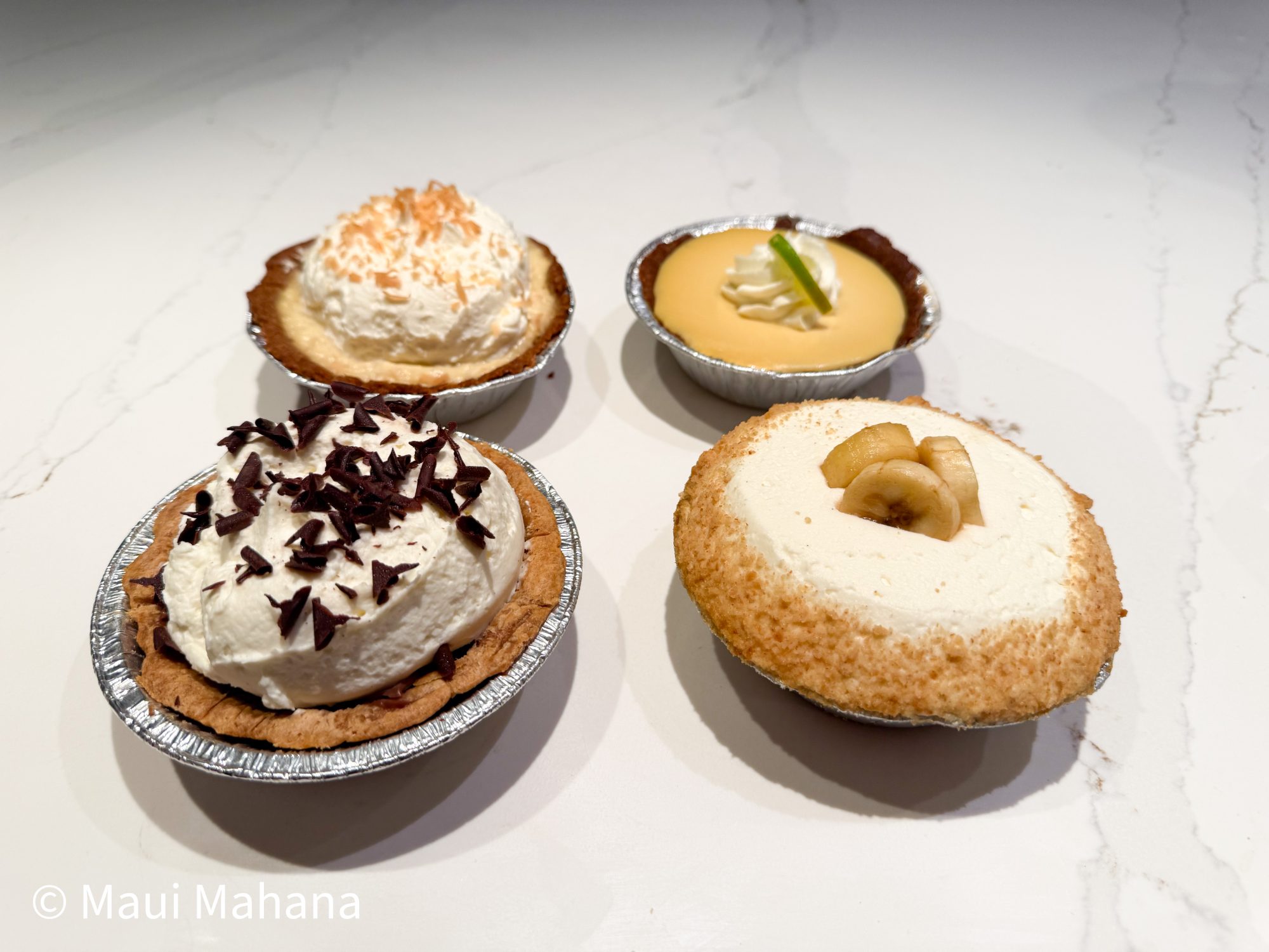 Four mini pies from Leoda's Kitchen & Pie Shop — coconut cream, lilikoi, chocolate cream, and banana cream